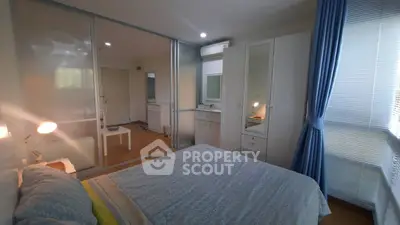 Spacious bedroom with modern decor and ample natural light, featuring a large wardrobe and stylish furnishings.