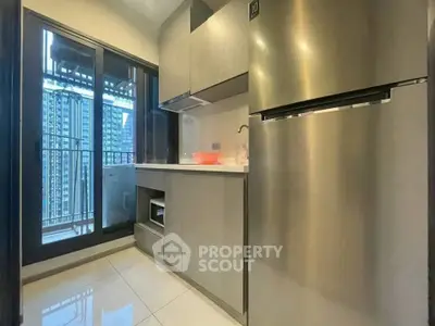 Modern kitchen with sleek cabinets and stainless steel fridge in high-rise apartment.