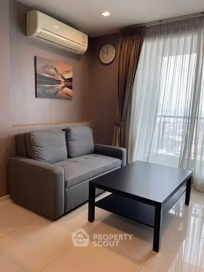 Modern living room with sleek sofa, air conditioning, and large window offering natural light.