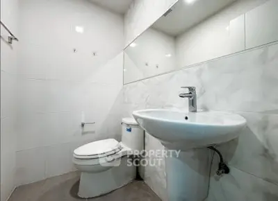 Modern bathroom with sleek white fixtures and large mirror