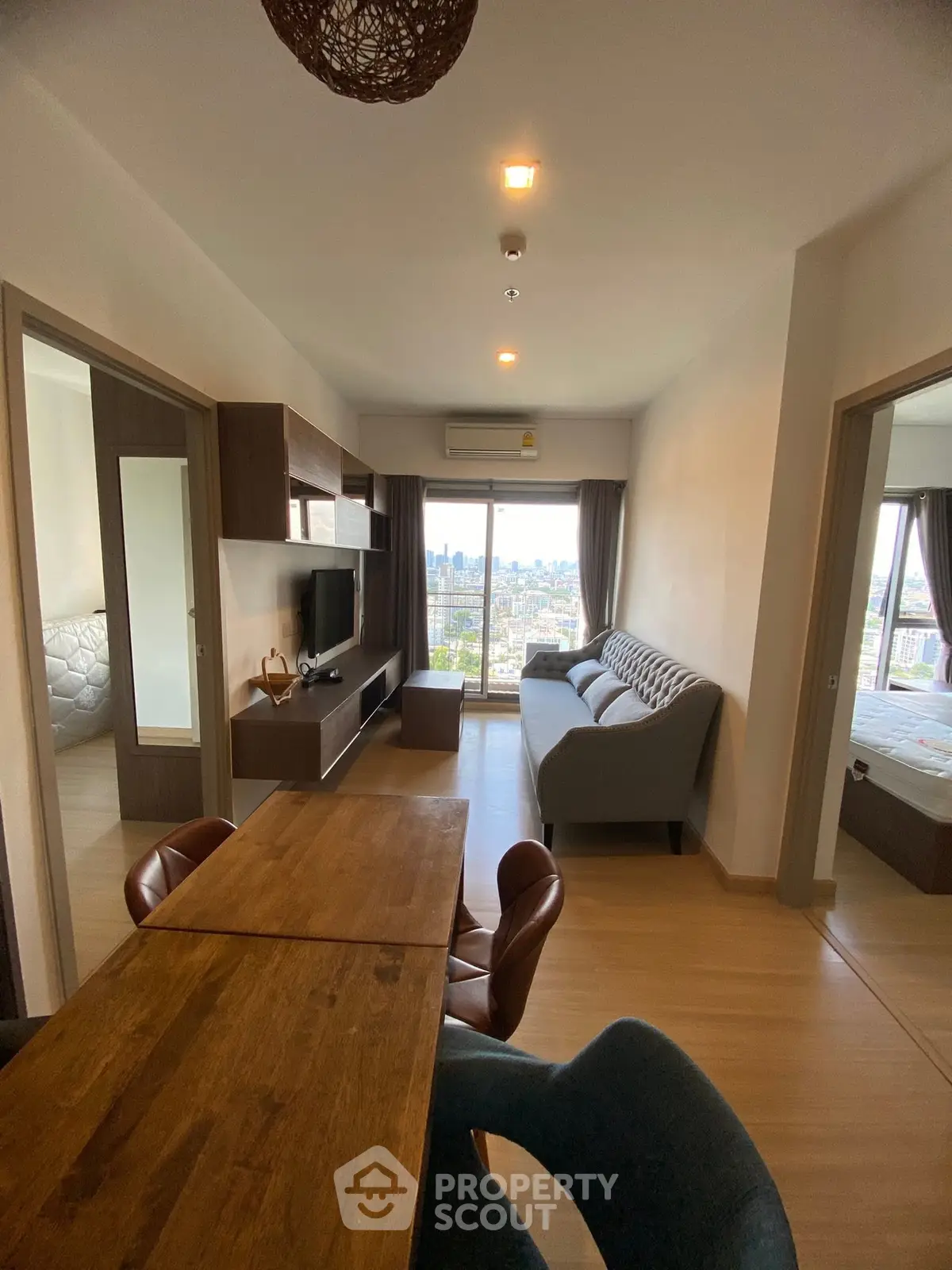 Modern living room with city view, stylish furniture, and wooden dining table in a cozy apartment.
