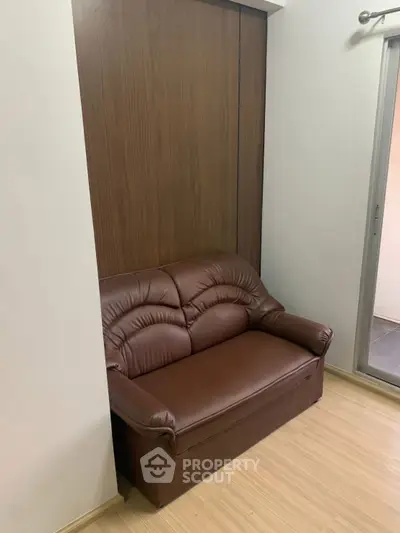 Cozy corner with brown leather sofa and wooden paneling, perfect for relaxation in a modern apartment.