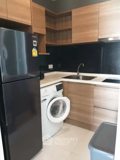 Modern kitchen with wooden cabinets, black fridge, and washing machine