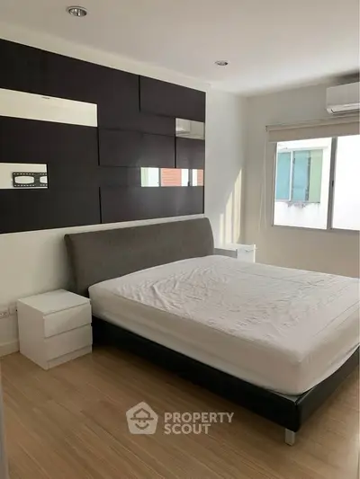 Modern bedroom with stylish decor and natural light, featuring a comfortable bed and sleek furnishings.