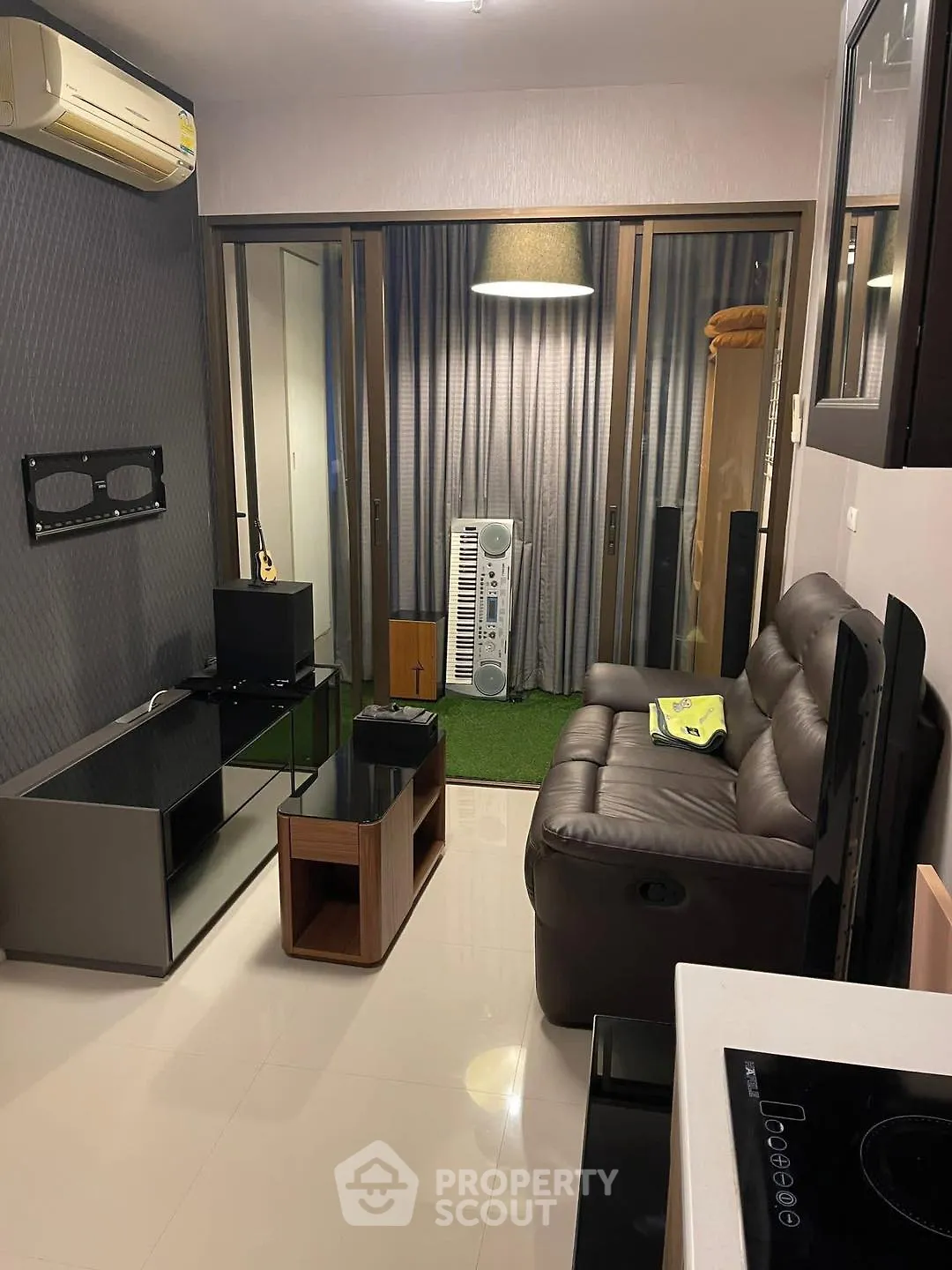 Modern living room with sleek furniture and air conditioning, featuring a cozy sofa and entertainment setup.