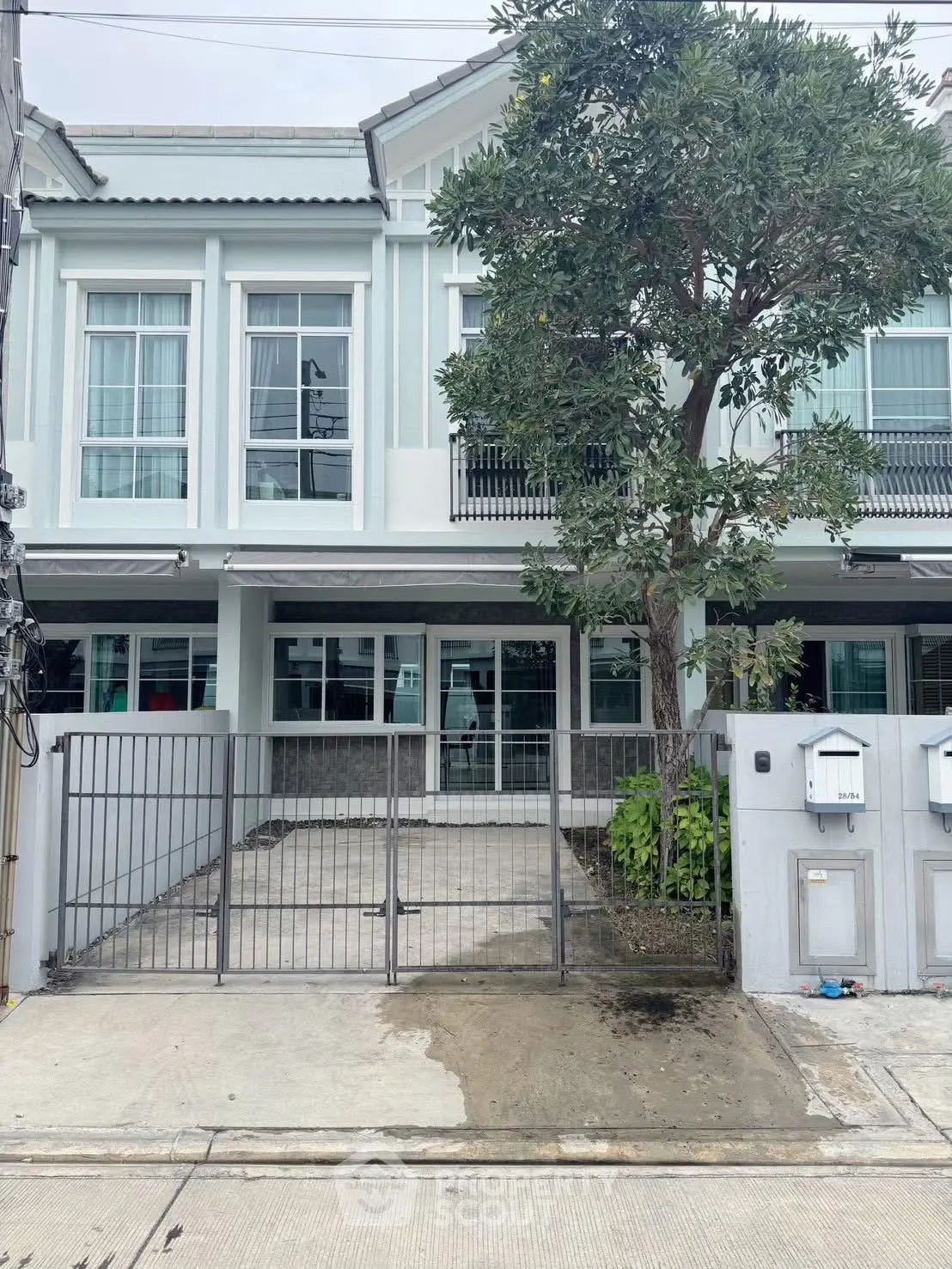 Modern townhouse exterior with gated driveway and lush tree