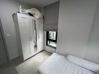 Cozy bedroom with white wardrobe and window view, minimalist design.