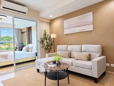 Modern living room with cozy sofa and view into elegant bedroom