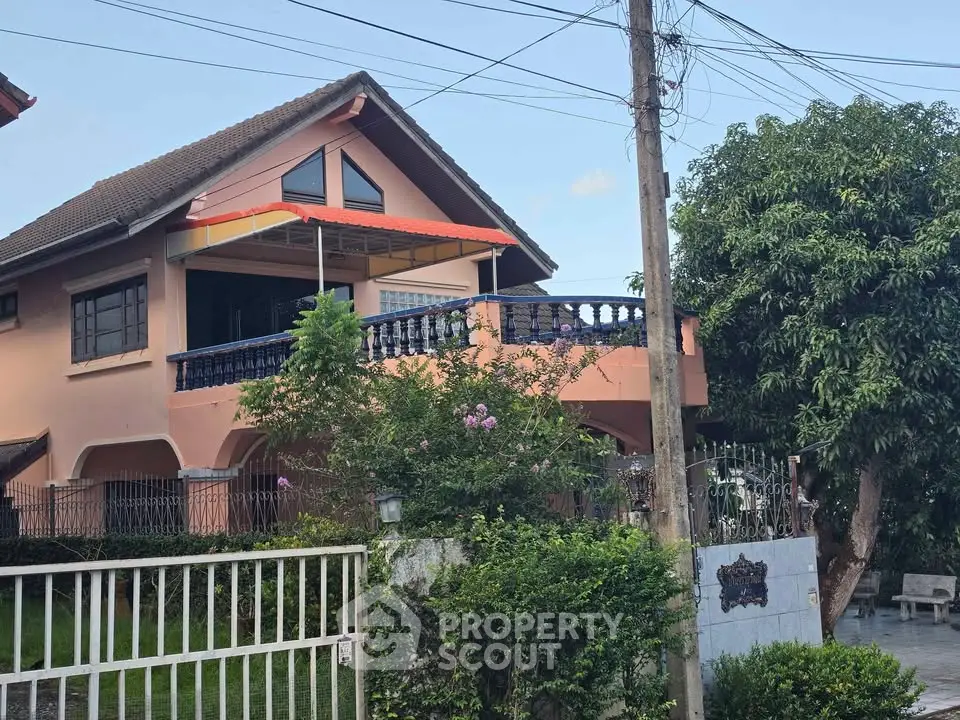 Charming two-story house with balcony and lush garden, perfect for family living.