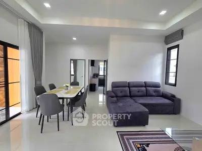 Modern living room with sleek furniture and open dining area, perfect for contemporary living.