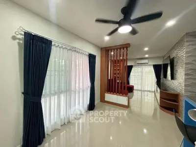 Spacious modern living room with ceiling fan and large windows