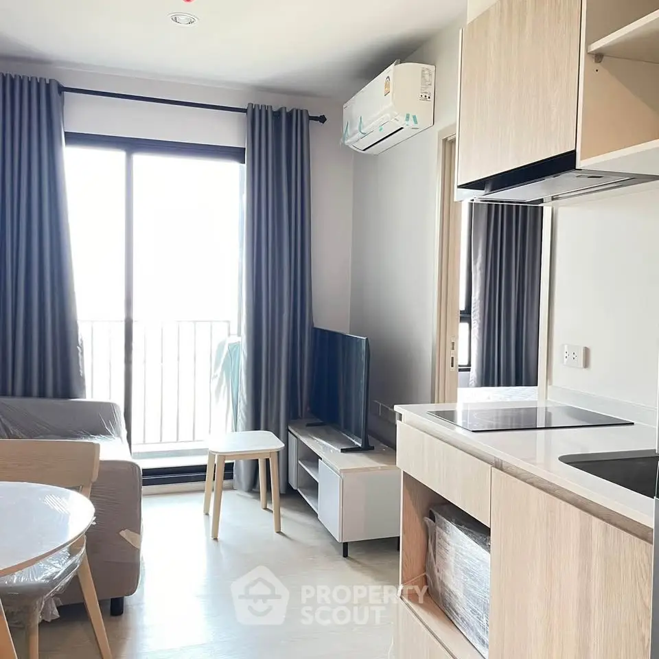 Modern living room with natural light, sleek furniture, and open kitchen layout in a stylish apartment.