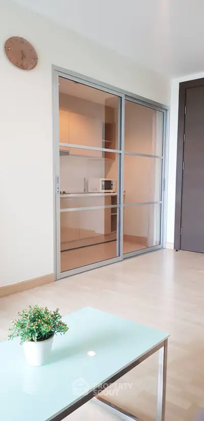 Modern living room with glass partition and sleek kitchen view