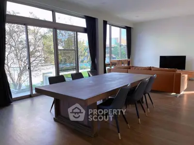 Spacious modern living room with large windows and elegant dining area.