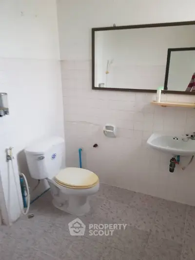 Simple bathroom with white tiles and basic fixtures, ideal for budget-friendly renovations.