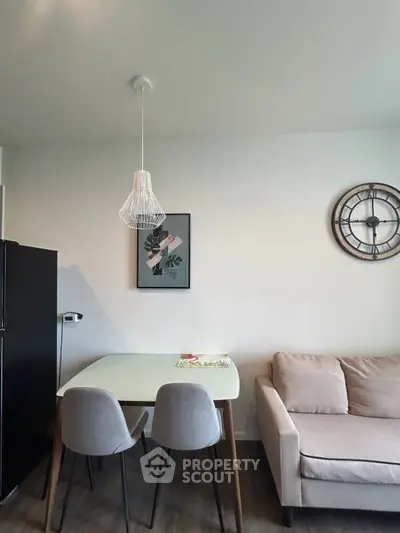 Modern living room with stylish decor, featuring a cozy sofa, dining table, and chic wall clock.