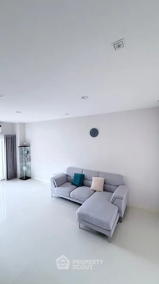 Spacious modern living room with elegant gray sofa and minimalist decor.