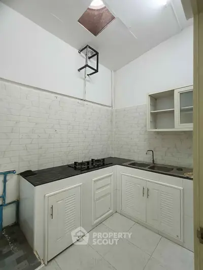 Compact kitchen with white cabinets and gas stove in modern apartment