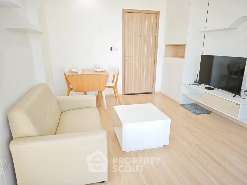 Modern living room with beige sofa, TV, and dining area in a cozy apartment.