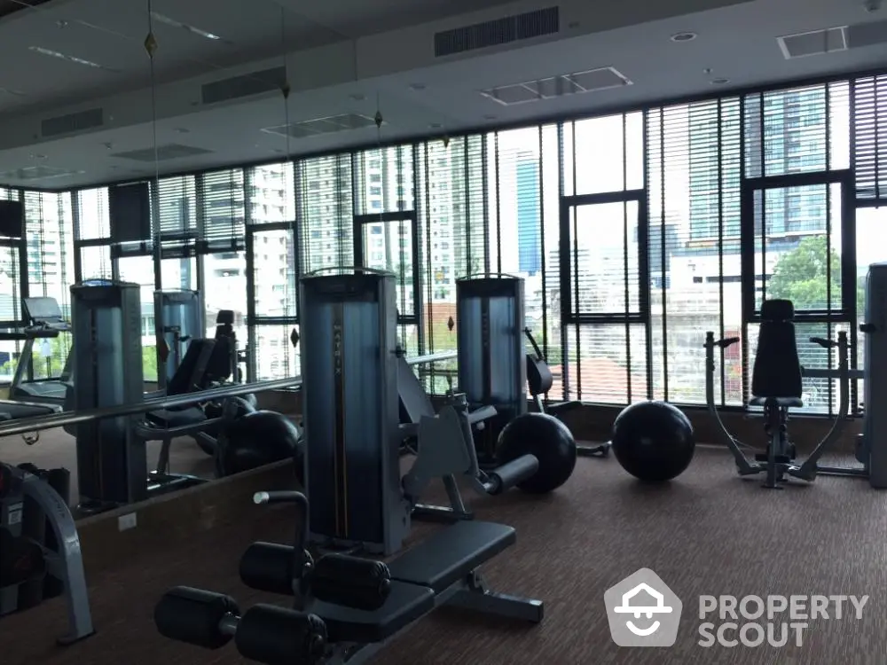 Modern gym with city view and state-of-the-art equipment in luxury building.