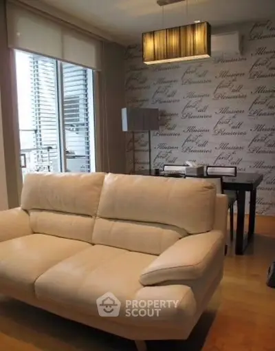 Modern living room with stylish sofa and dining area, featuring elegant lighting and large windows.