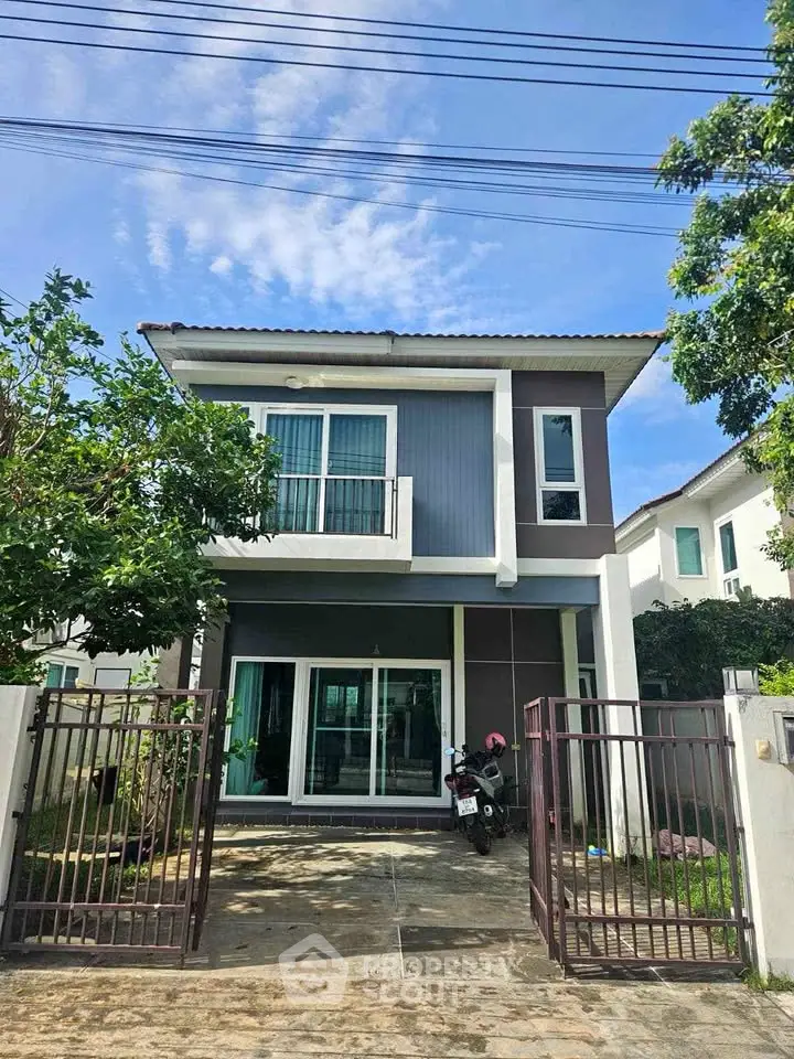 Modern two-story house with gated entrance and driveway, perfect for family living.