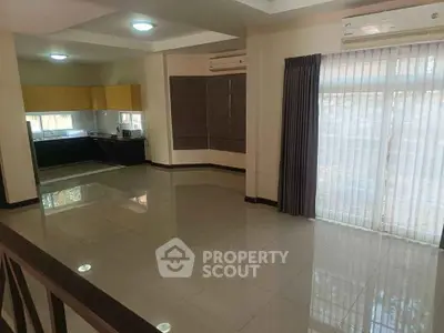 Spacious open-plan living room with modern kitchen and large windows.