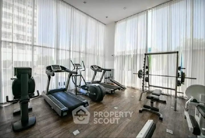 Spacious modern gym with state-of-the-art equipment and floor-to-ceiling windows.