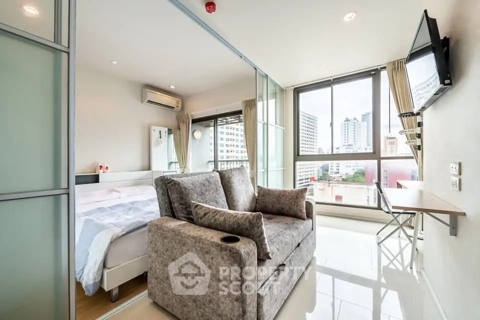 Modern studio apartment with city view, featuring a cozy living area and bedroom separated by sliding glass doors.
