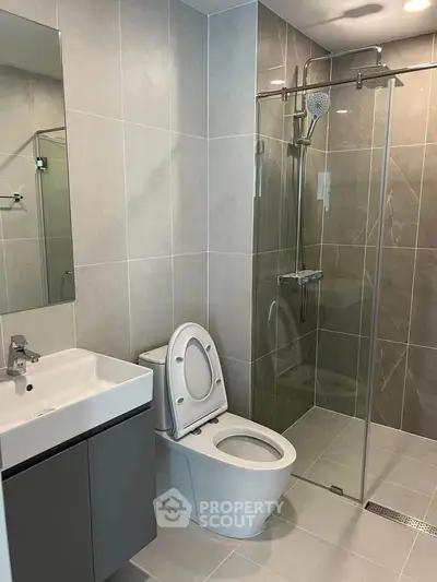 Modern bathroom with sleek design, featuring a glass shower enclosure and contemporary fixtures.