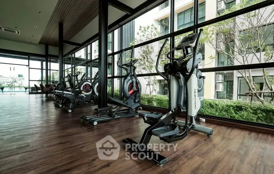 Modern gym with large windows and fitness equipment in luxury apartment building.