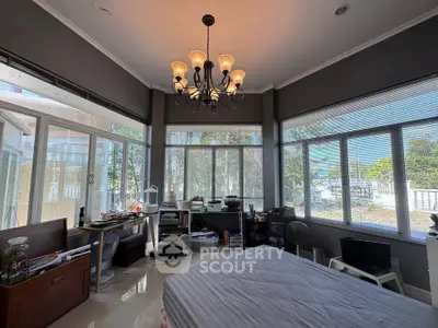 Spacious bedroom with large windows and elegant chandelier, offering a serene view.