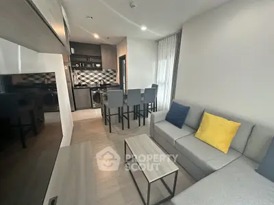 Modern living room with open kitchen, stylish decor, and cozy seating area in a contemporary apartment.