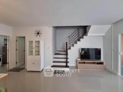 Modern living room with sleek staircase and stylish TV setup