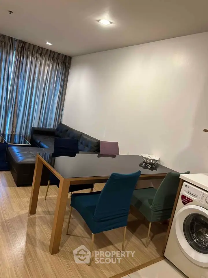 Modern living room with dining area and washing machine, featuring sleek furniture and wooden flooring.
