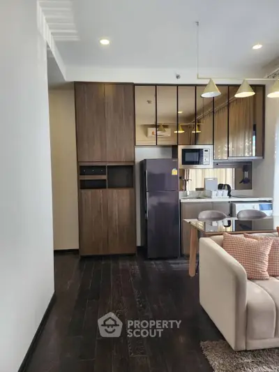 Modern living room with open kitchen, featuring sleek appliances and stylish decor.