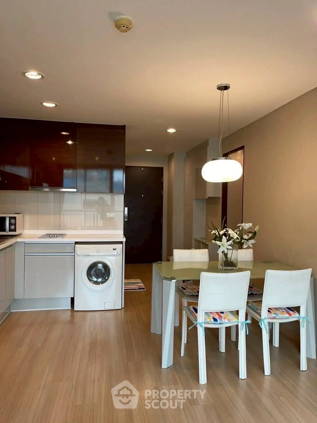 Modern kitchen with dining area and washing machine, sleek design and bright lighting.