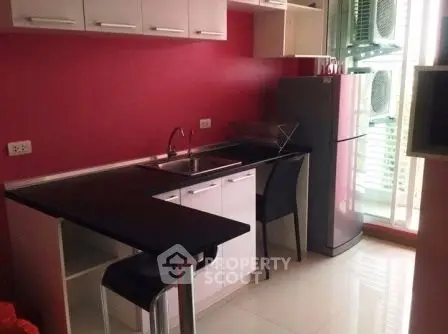 Modern kitchen with sleek red walls, compact layout, and stainless steel appliances.