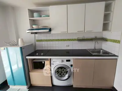Compact kitchen with washing machine and retro fridge in modern apartment