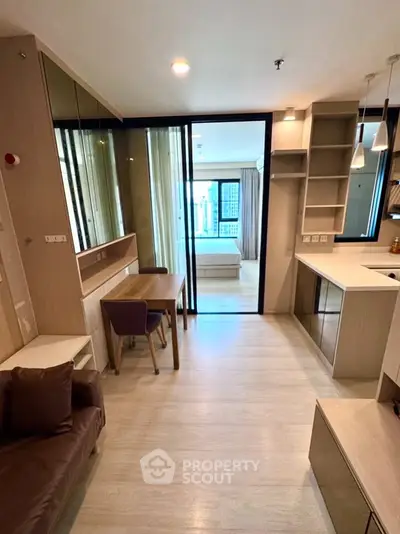 Modern open-plan living room with sleek kitchen and cozy dining area, featuring stylish decor and ample natural light.