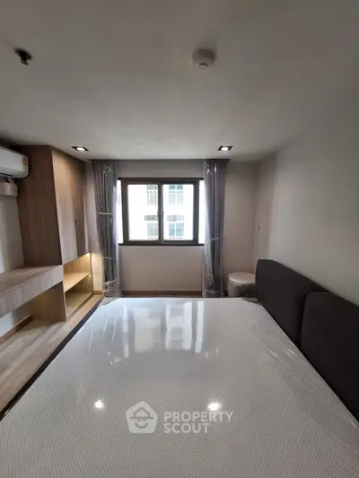 Modern bedroom with large window and sleek furnishings in urban apartment