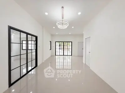 Spacious modern living room with sleek glass doors and elegant lighting.