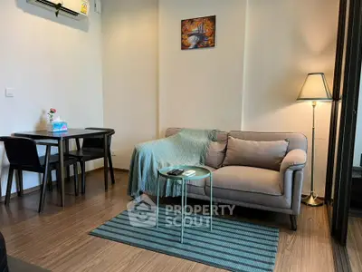 Cozy living room with modern decor, featuring a comfortable sofa, stylish lamp, and dining area.