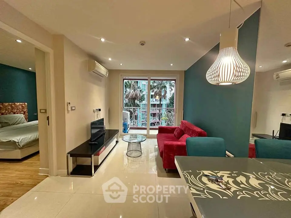 Modern living room with vibrant decor and balcony view, featuring stylish furniture and elegant lighting.