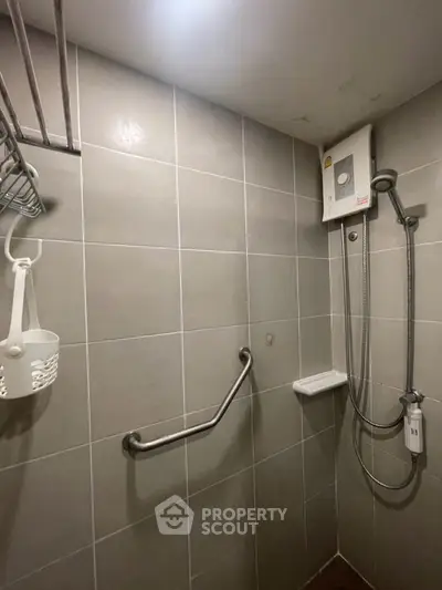 Modern bathroom with shower, grab bar, and water heater in tiled interior.