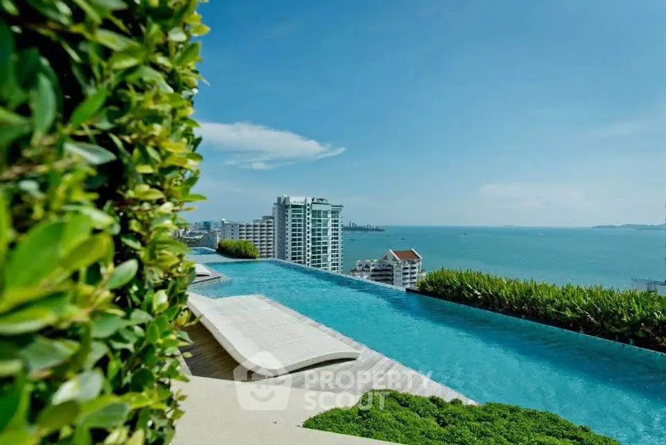 Luxurious rooftop infinity pool with stunning ocean view and lush greenery in a high-rise building.