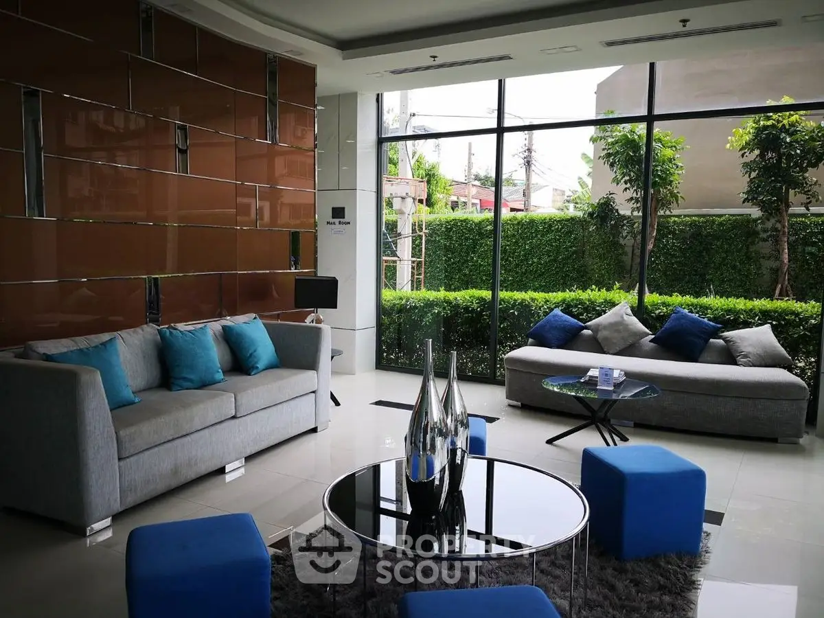 Modern living room with stylish decor and large windows overlooking lush greenery.