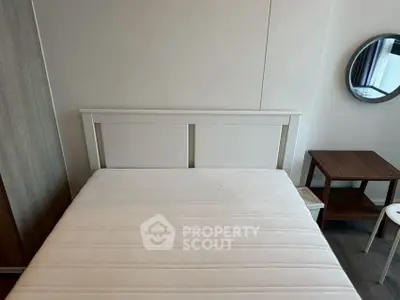 Modern bedroom with minimalist design featuring a white bed frame and round mirror.