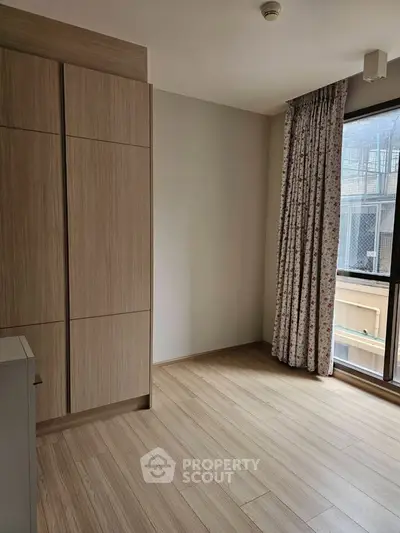 Spacious bedroom with large window and built-in wardrobe in modern apartment