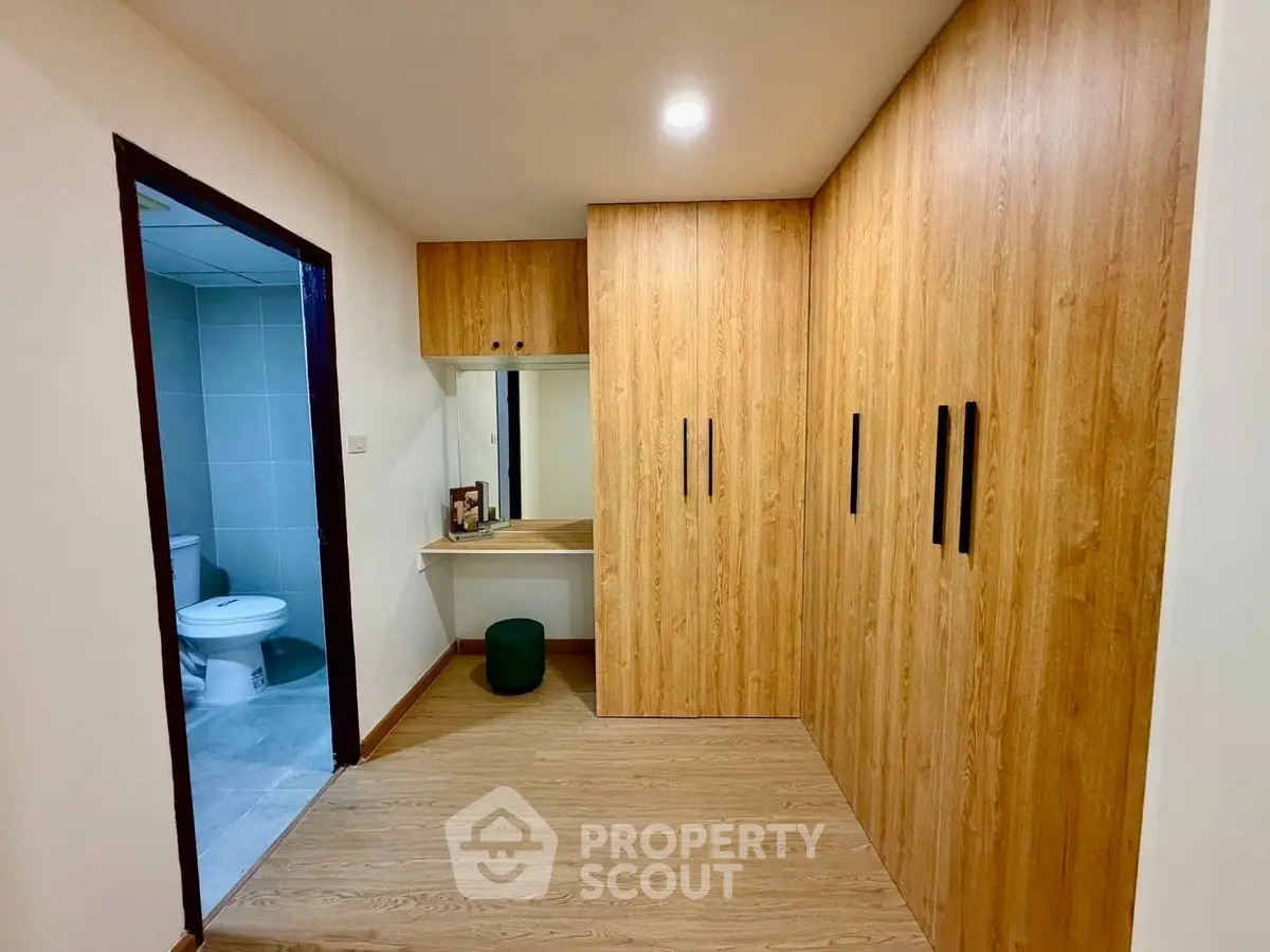 Spacious bedroom with wooden flooring and built-in wardrobe, adjacent to modern bathroom.